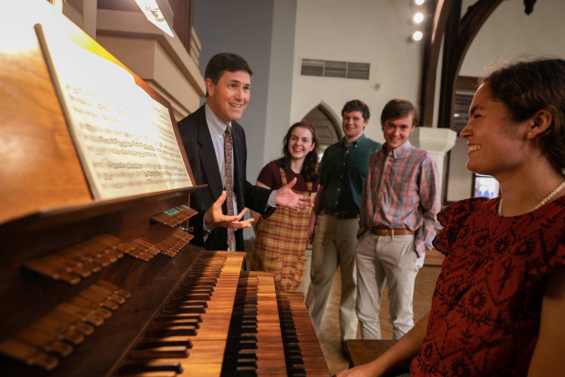 Students standing around a piano
