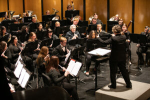 Conductor and wind ensemble players on stage at the Grand Opera House