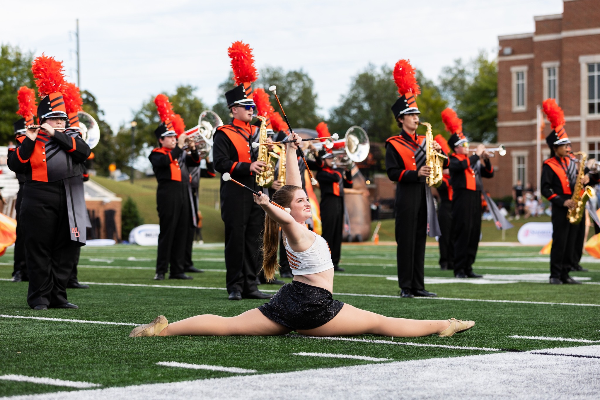 Marching Band members on the football field with a baton twirler in front