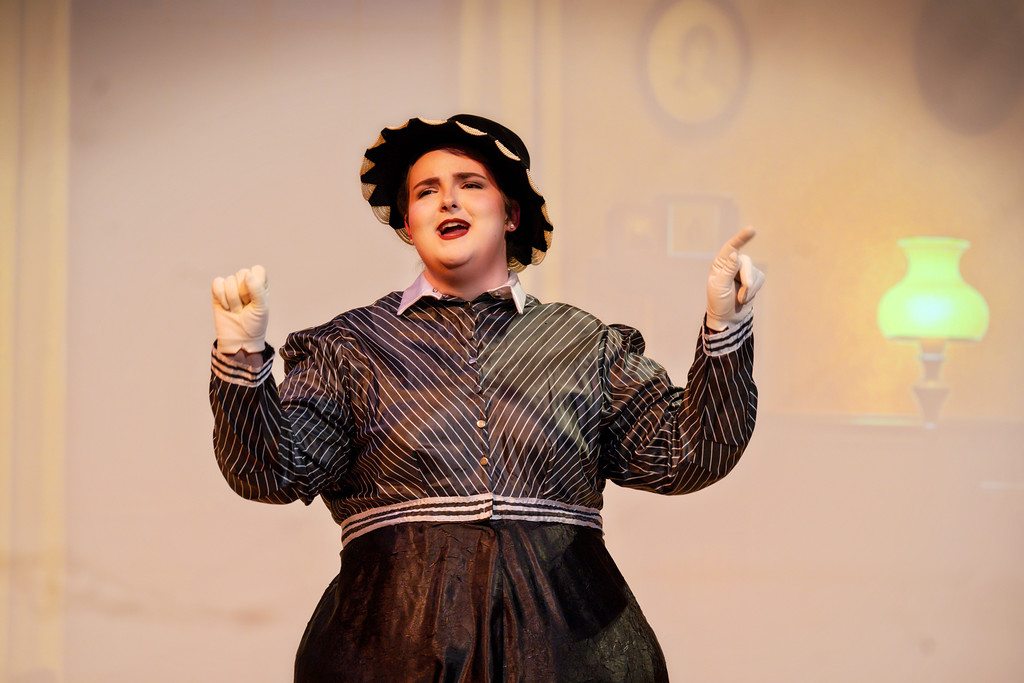 Woman sings on stage wearing black 1920s clothing