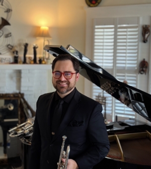 Kyle Mallari holding a trumpet, standing in front of a grand piano