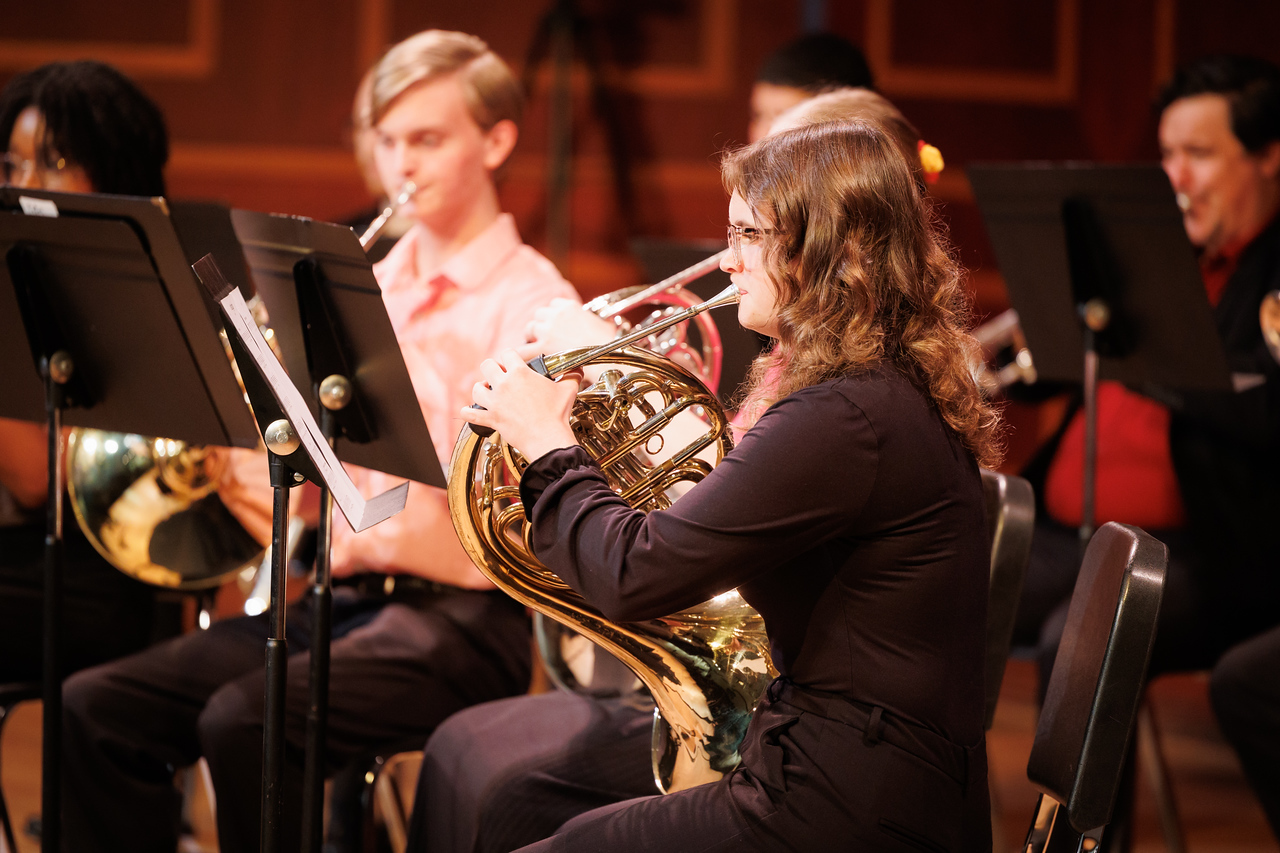 a french horn player on stage with the chamber wind ensemble