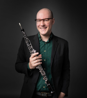 Zach Boeding headshot with oboe