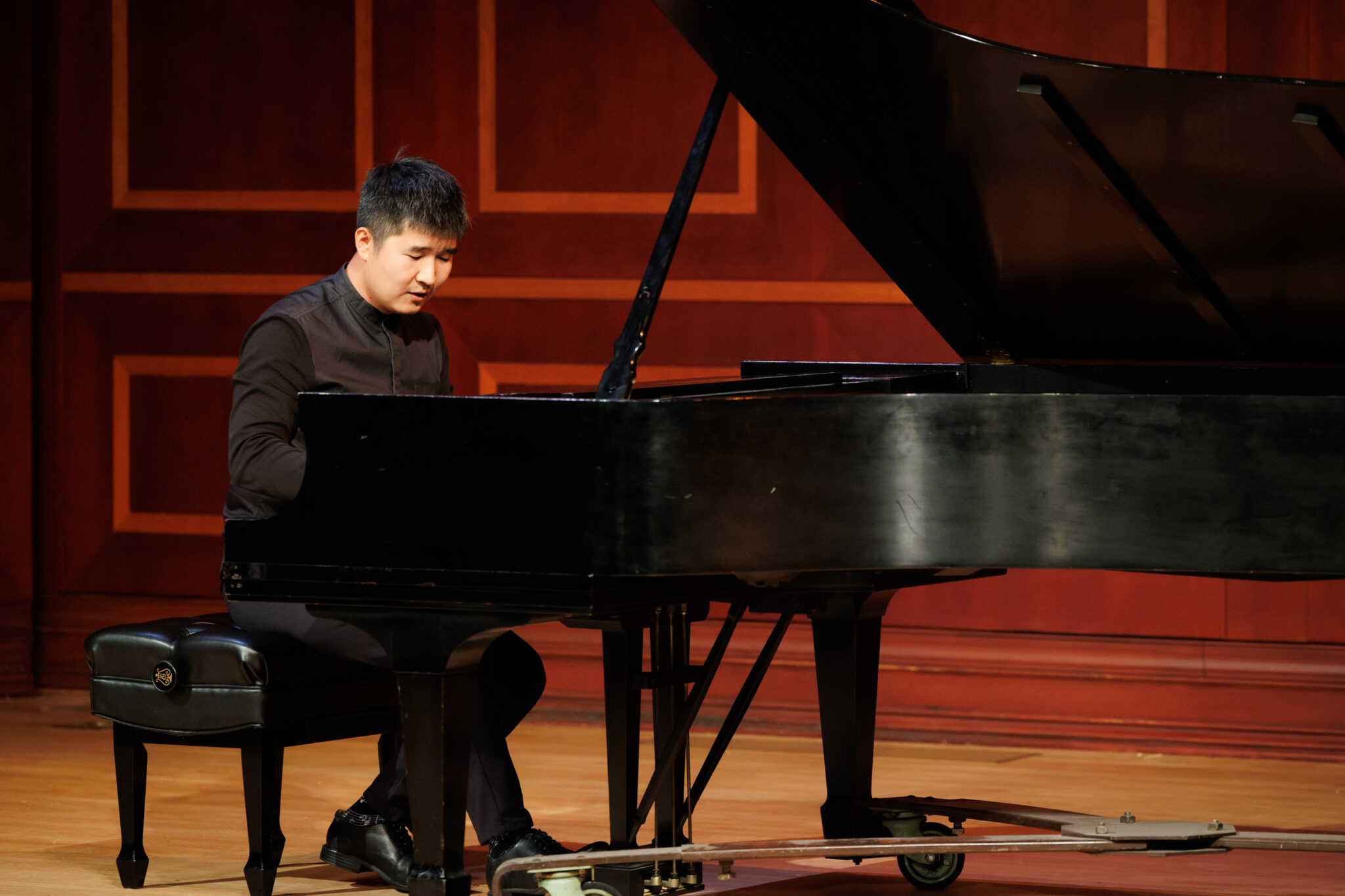Dr. Nicholas Zehao Bai perform on stage at a grand piano